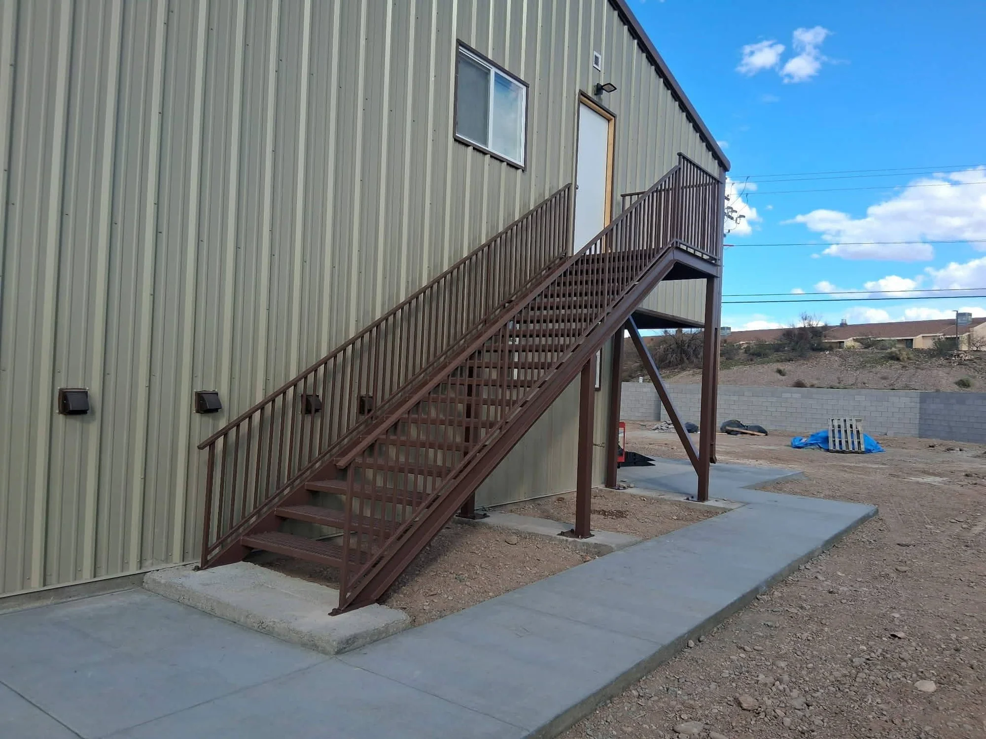 Completed exterior steel stairs beside a metal building
