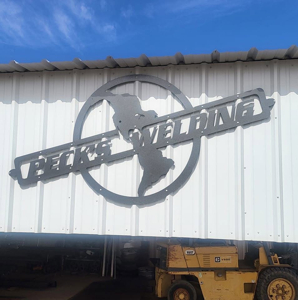 Peck’s Welding fabricated shop sign on a metal building